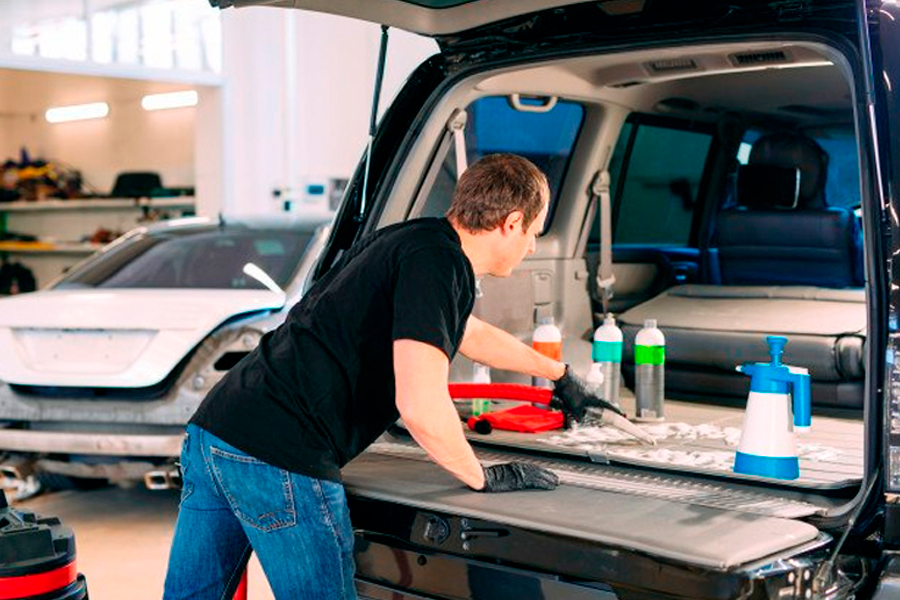 A Man Cleaning the Trunk of a Car